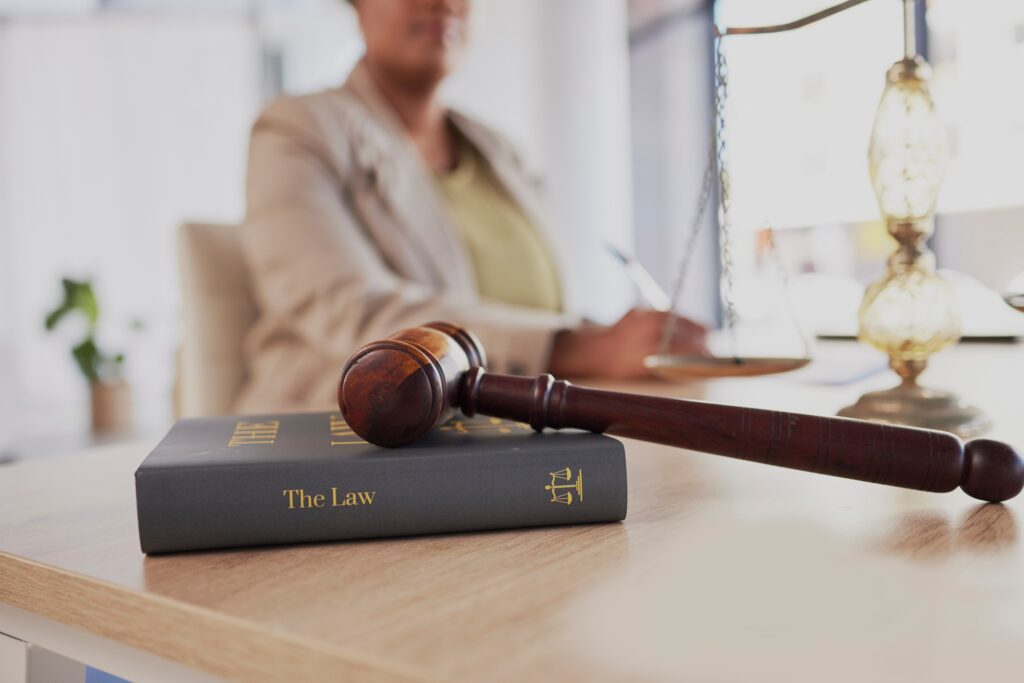 Gavel, law firm and books on table of attorney in office for judge, justice and court trial. Closeu